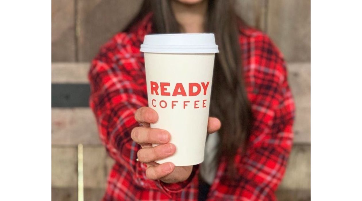 Ready Coffee logo on white cup held by person in red flannel